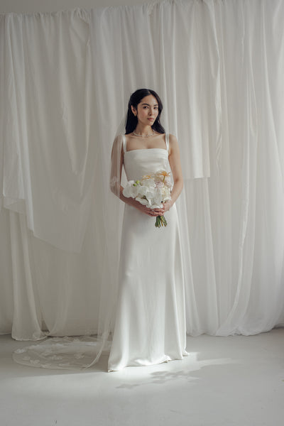 Die Braut trägt einen langen Schleier, die mir einer Blumenspitze bestickt ist