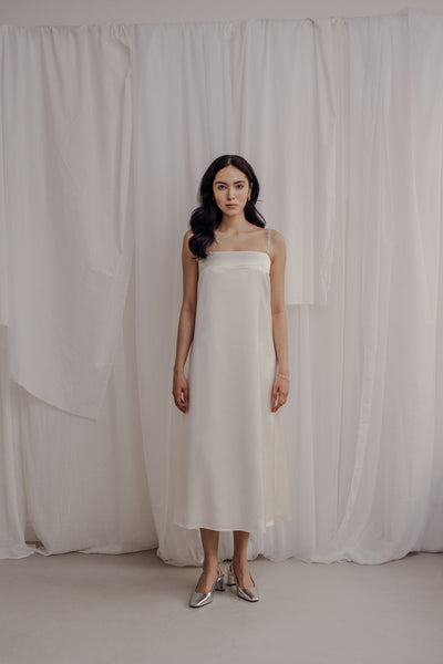 Braut die ein Brautkleid aus Viskose trägt. das Brautkleid fällt schlicht und hat 2 mit Perlen bestickte Träger