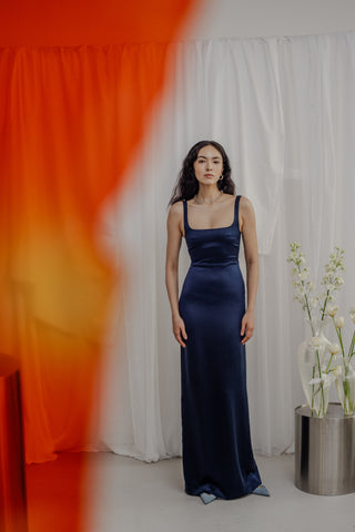 Hochzeitsgast, der ein bodenlanges marineblaues Kleid trägt. Das Kleid
